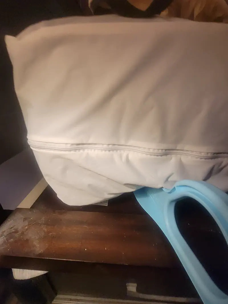 Light blue mattress lifter tucked under the corner of a mattress with a white fitted sheet