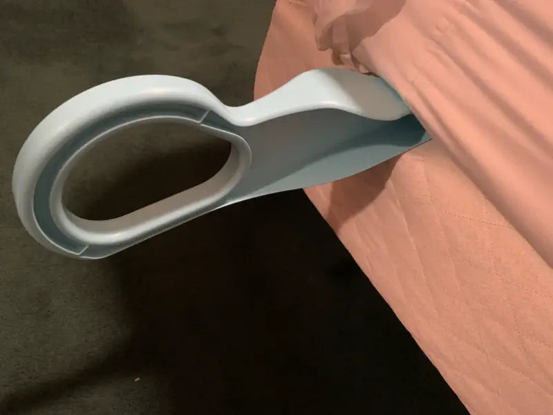 Close-up of a light blue mattress lifter under a mattress with a peach fitted sheet