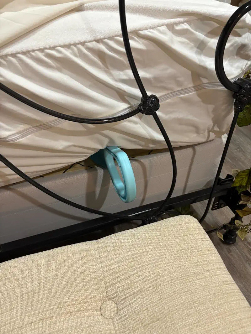 Light blue mattress lifter under a mattress on a black metal bed frame